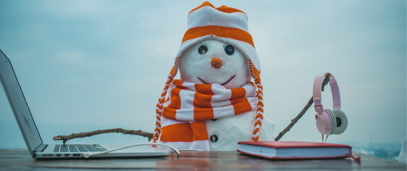 A snowman with a laptop, headphones and a book.